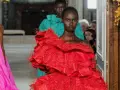 Una modelo luce un espectacular vestido rojo valentino con volantes y plumas. Detrás, otra modelo con un vestido turquesa.