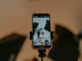 Teléfono móvil grabando a una persona con una caja, montado en un trípode.