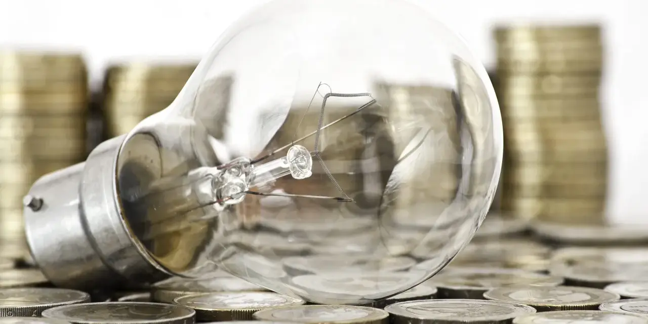 Bombilla sobre monedas, sugiriendo ideas valiosas y técnicas de impresión para la innovación.