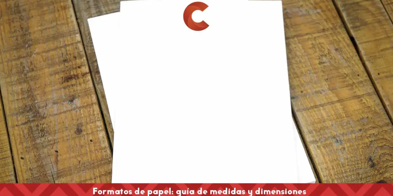 Dos hojas de papel blanco apiladas sobre una mesa de madera. Una tiene un logo rojo en forma de C. Ideal para comparar tamaños din a4 y din a5.