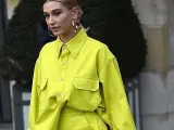 Modelo luce una camisa de **color lima** vibrante, con bolsillos frontales y grandes aros plateados.