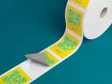 Rollo de etiquetas amarillas con códigos QR azules y números, listo para imprimir etiquetas.