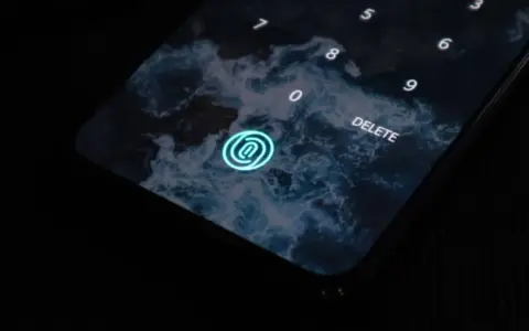 Pantalla de bloqueo de un móvil con fondo de olas. Un icono de huella dactilar brilla en azul. Los tipos móviles evolucionan.