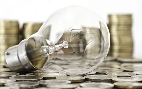 Bombilla sobre monedas, sugiriendo ideas valiosas y técnicas de impresión para la innovación.