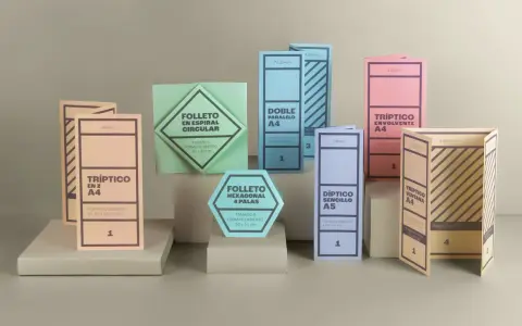 Varios folletos y dípticos de diferentes formas y colores, algunos abiertos y otros cerrados.
