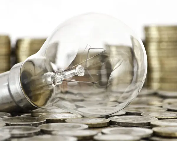 Bombilla sobre monedas, sugiriendo ideas valiosas y técnicas de impresión para la innovación.