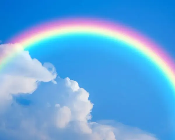 Un arcoíris con sus vibrantes colores del arcoiris cruza un cielo azul claro con nubes blancas.