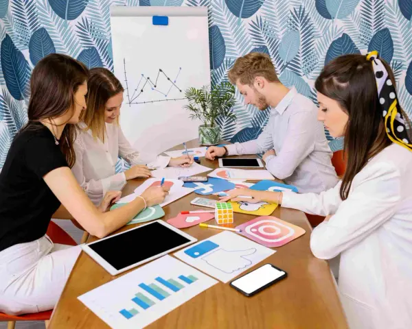 Equipo discutiendo estrategias de marketing digital, con iconos de redes sociales y gráficos. Parecen estar planeando una campaña de "fake out of home".