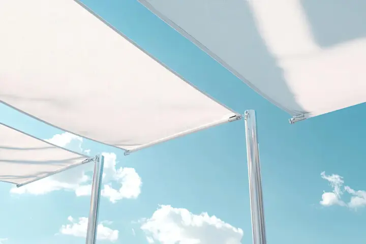 Detalles de cómo colocar una lona tensada sobre postes metálicos, con cielo azul y nubes de fondo.