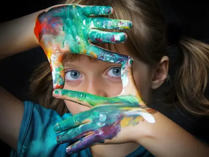 Niña con manos pintadas de colores, creando un marco. Fotografías sin derechos de autor para inspirar tu creatividad.