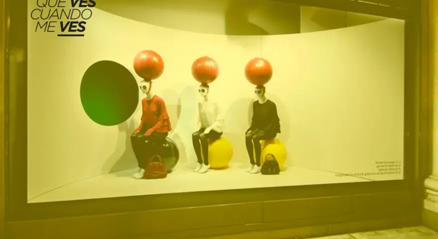 Maniquíes con esferas rojas en la cabeza, sentados en pelotas, exhiben ropa. Un ejemplo de **que es el visual merchandising** para atraer miradas.