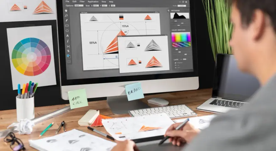 Diseñador trabajando en un programa de diseño gráfico gratis, creando un logo. Se ven bocetos, paleta de colores y notas.