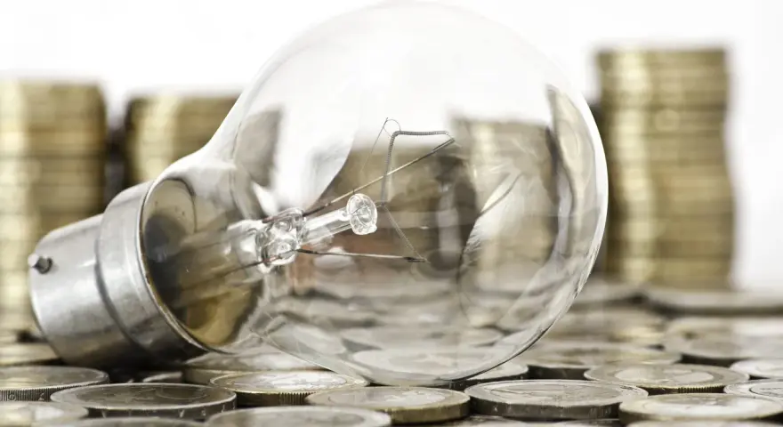 Bombilla sobre monedas, sugiriendo ideas valiosas y técnicas de impresión para la innovación.