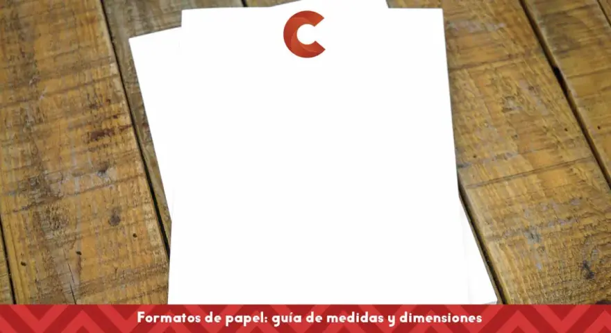 Dos hojas de papel blanco apiladas sobre una mesa de madera. Una tiene un logo rojo en forma de C. Ideal para comparar tamaños din a4 y din a5.