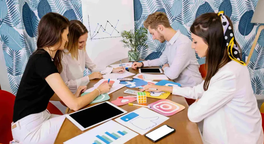 Equipo discutiendo estrategias de marketing digital, con iconos de redes sociales y gráficos. Parecen estar planeando una campaña de "fake out of home".