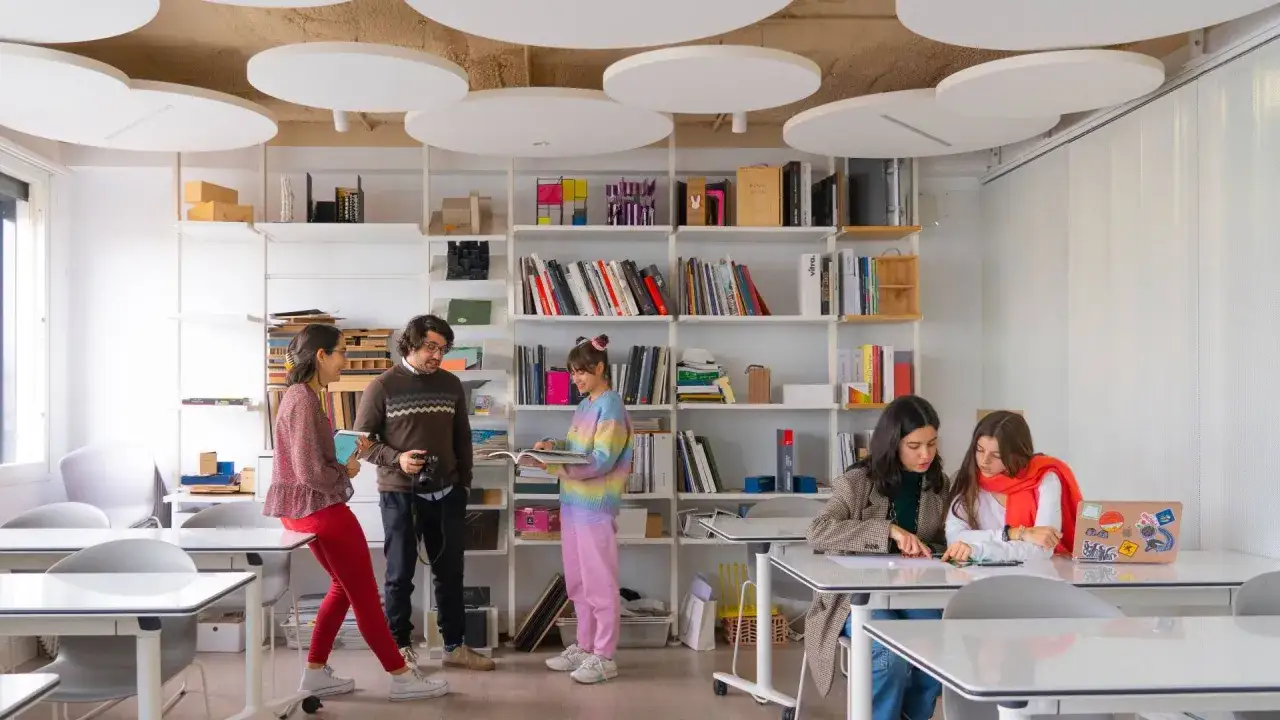 Estudiantes colaboran en un aula moderna, inspiradora para quienes buscan donde estudiar diseño gráfico.