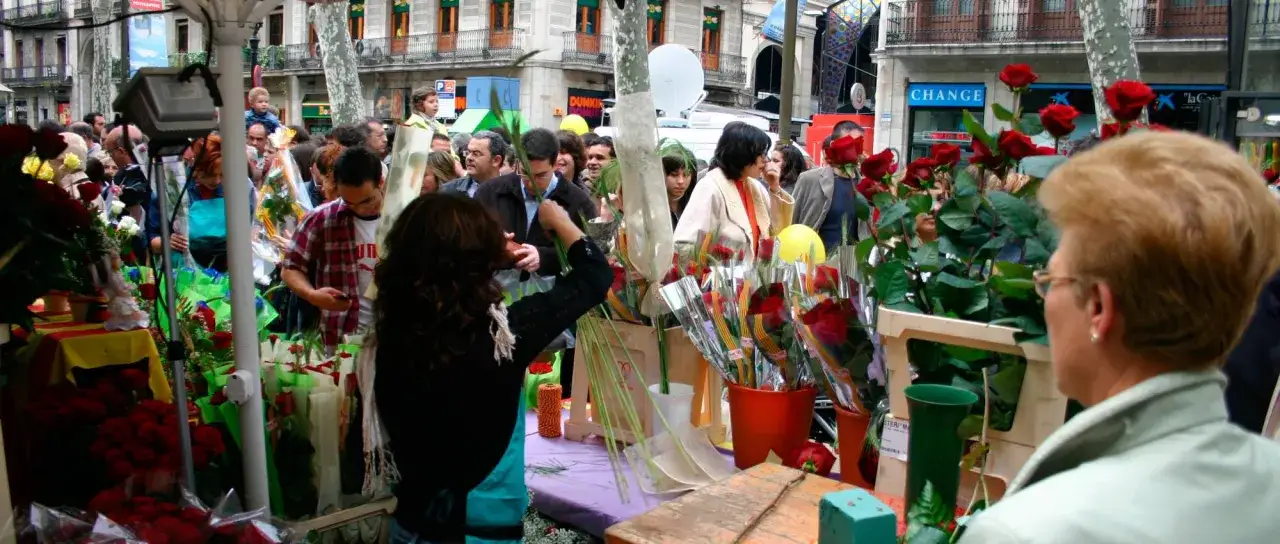 Gente comprando rosas en un puesto callejero para celebrar el día del libro.