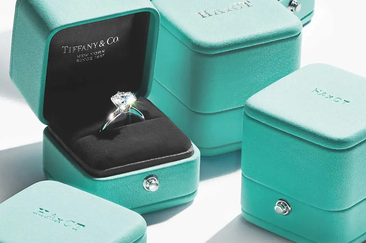 Anillo de compromiso brillante en una caja azul tiffany abierta. Otras cajas del mismo color azul tiffany rodean la principal.