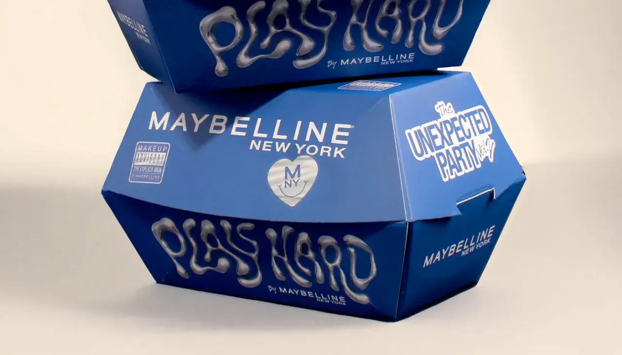 Cajas azules de Maybelline apiladas, con el lema 