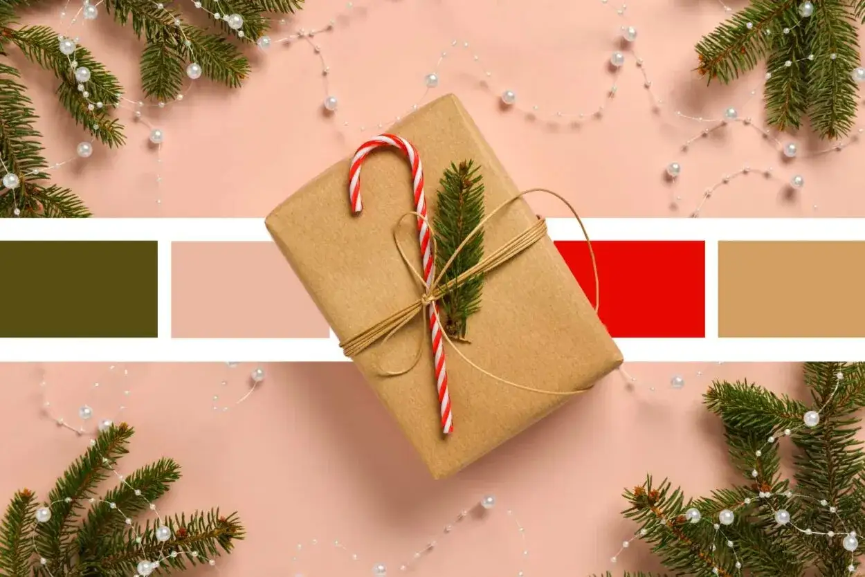Paleta de colores de la navidad: regalo envuelto en papel kraft, bastón de caramelo, rama de abeto y guirnalda de perlas sobre fondo rosa.